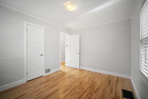 Second bedroom with light wood-style floors, ornamental molding, and closet