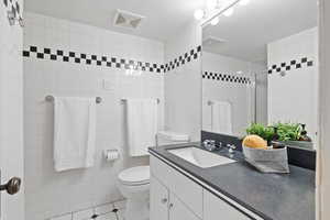 Bathroom with a tile shower, vanity, and light tile patterned floors