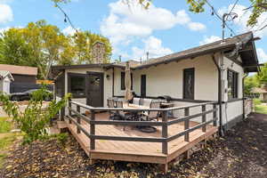 Rear view of home with composite deck and access to sunroom