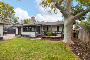 Backyard and rear view of house with a wooden deck and mature trees