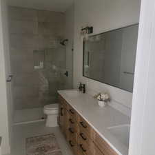 Bathroom featuring double vanity, walk in shower, and light tile patterned floors