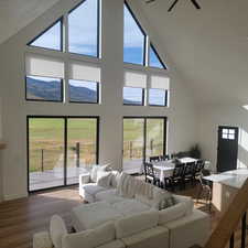 Living area featuring high vaulted ceiling, wood finished floors, and ceiling fan
