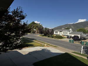 View of asphalt street featuring sidewalks, a mountain view, and curbs