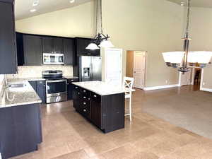 Kitchen with a chandelier, backsplash, stainless steel appliances, a breakfast bar, and light stone counters
