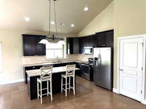 Kitchen featuring stainless steel appliances, a center island, decorative light fixtures, a breakfast bar area, and tasteful backsplash