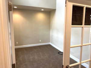 Unfurnished room with dark colored carpet and recessed lighting