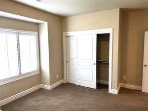 Unfurnished bedroom featuring dark colored carpet and a closet