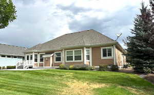 Back of property featuring a yard and roof with shingles
