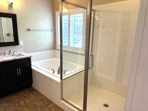 Full bath with a shower stall, vanity, and a garden tub