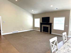 Unfurnished living room with a textured ceiling, carpet floors, a tile fireplace, recessed lighting, and tile patterned flooring