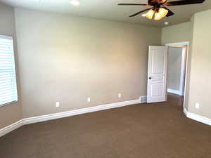 Spare room featuring dark colored carpet, a ceiling fan, and a textured ceiling