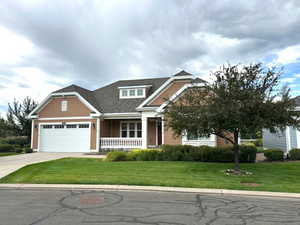 Craftsman-style home featuring a front lawn, a porch, driveway, and an attached garage