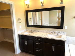Full bathroom featuring a spacious closet, double vanity, and a garden tub