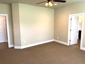 Empty room with dark carpet and ceiling fan