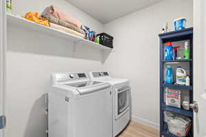 Laundry area featuring light wood-style floors and separate washer and dryer