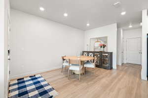 Dining space with light wood finished floors and recessed lighting