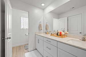 Bathroom featuring double vanity and light wood-style flooring