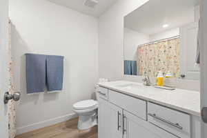 Full bathroom with vanity, light wood-style floors, and curtained shower