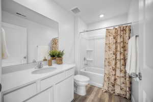 Full bathroom with shower / bathtub combination with curtain, vanity, and dark wood finished floors