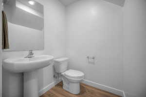 Half bathroom with baseboards and wood finished floors