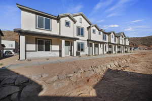 Back of house with stucco siding, stone siding, a porch, and a residential view