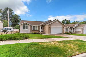 Single story home featuring an attached garage, brick siding, driveway, and a shingled roof