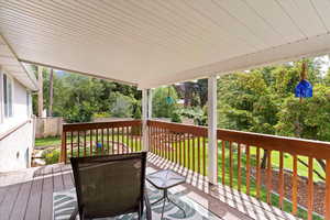 Wooden deck featuring a lawn and view of scattered trees