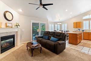 Living room featuring light tile patterned floors, vaulted ceiling, recessed lighting, a ceiling fan, and a high end fireplace