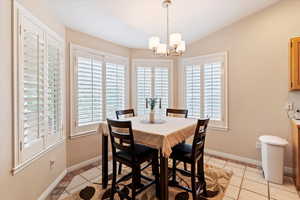 Dining area with healthy amount of natural light, light tile patterned floors, vaulted ceiling, and a chandelier