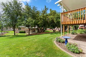 View of grassy yard featuring a wooden deck