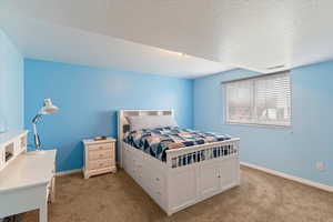 Bedroom with light carpet and a textured ceiling
