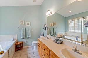 Bathroom featuring light tile patterned floors, double vanity, a bath, and recessed lighting