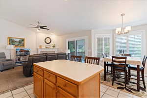 Kitchen featuring light countertops, decorative light fixtures, lofted ceiling, light tile patterned flooring, and brown cabinetry
