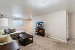 Carpeted living area featuring a textured ceiling and baseboards