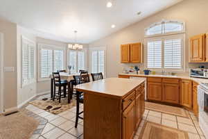 Kitchen featuring light countertops, lofted ceiling, a center island, light tile patterned flooring, and recessed lighting