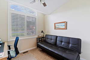 Carpeted office with lofted ceiling and ceiling fan