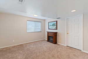 Unfurnished living room featuring a glass covered fireplace, light carpet, and recessed lighting