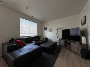 Living area with light wood finished floors, a textured ceiling, and recessed lighting