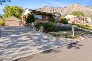 Ranch-style home featuring a detached garage, an outbuilding, a mountain view, and brick siding