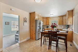 Kitchen featuring light countertops, light brown cabinetry, stainless steel refrigerator with ice dispenser, light tile patterned floors, and light colored carpet