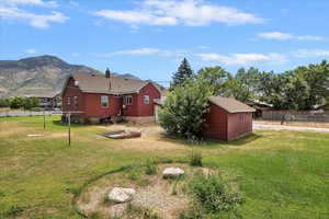 Back of property featuring a chimney, an outdoor structure, a mountain view, and roof with shingles
