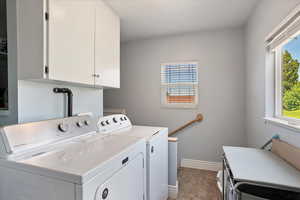Laundry area featuring washing machine and dryer, tile patterned flooring, and cabinet space