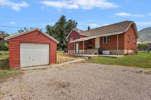View of front of property featuring a garage, gravel driveway, an outbuilding, a porch, and a mountain view