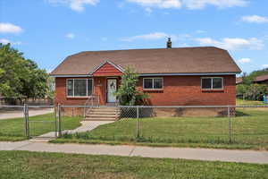 View of front of house featuring a gate, a fenced front yard, brick siding, and a chimney