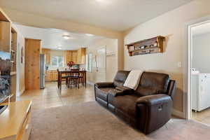 Living room with light tile patterned flooring, washer / dryer, and light carpet
