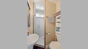 Full bath featuring a shower stall and toilet