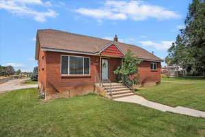 Bungalow-style house featuring a chimney, a front lawn, and a shingled roof