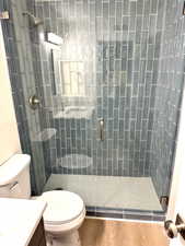 Full bath with vanity, a stall shower, and wood finished floors