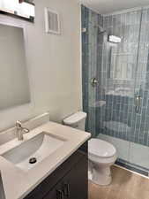 Bathroom featuring vanity, a shower stall, and wood finished floors