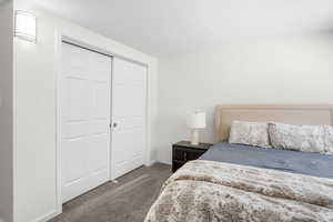 Bedroom featuring dark carpet, a textured ceiling, and a closet